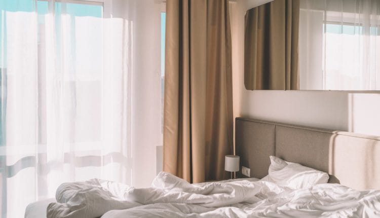 white bed linen near white window curtain