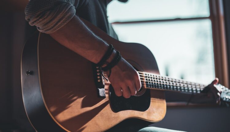 man playing acoustic guitar selective focus photography