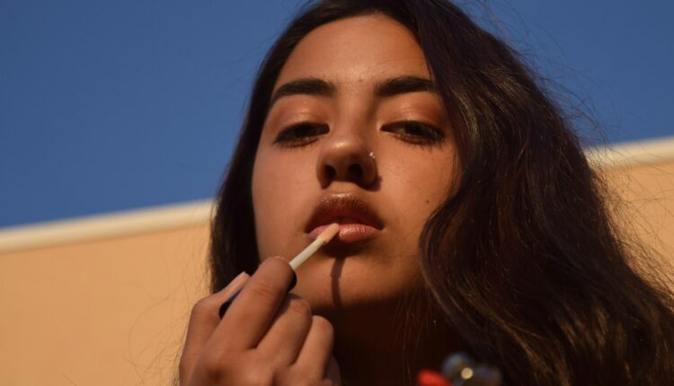 a woman smoking a cigarette with a blue sky in the background